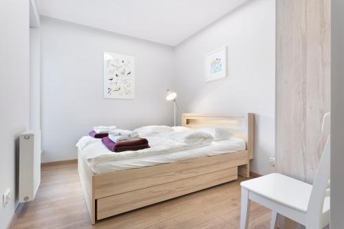 ヴロツワフにあるSpokojny i komfortowy apartament wśród zieleniのベッドルーム1室(白いシーツと椅子付)