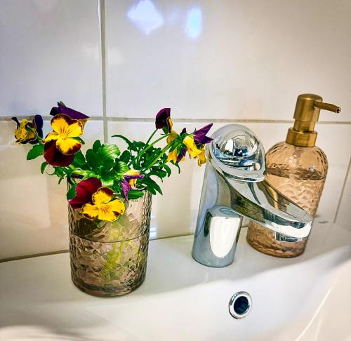 a bathroom sink with flowers and a bottle of soap at Nordic Lodges in Malmö