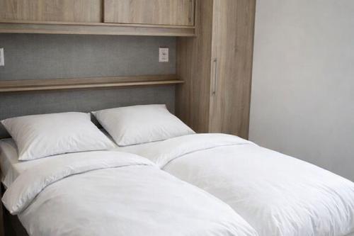 a large bed with white sheets and pillows at Odin Camping AS in Svensrud