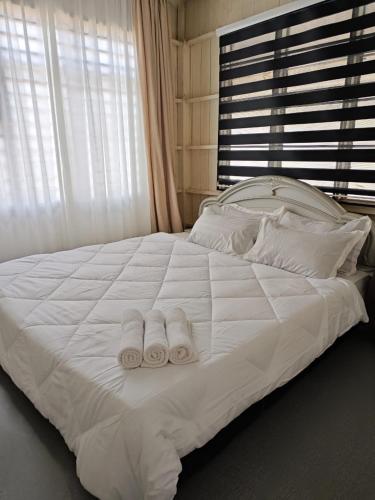 a white bed with two towels on top of it at Rooma Kayu in Kampong Alor Fatimah