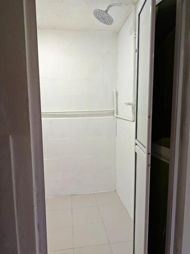 a bathroom with a shower with a white tile floor at Rooma Kayu in Kampong Alor Fatimah