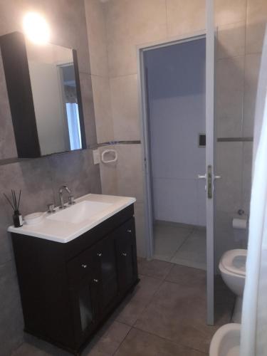 a bathroom with a sink and a toilet and a mirror at La quinta de Hostal in Rosario