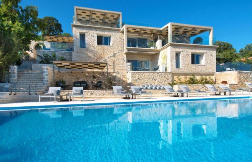 a villa with a swimming pool in front of a house at White Orchid in Syvota