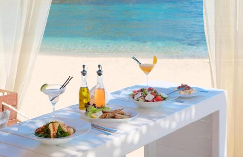 a table with plates of food and drinks on the beach at White Orchid in Syvota