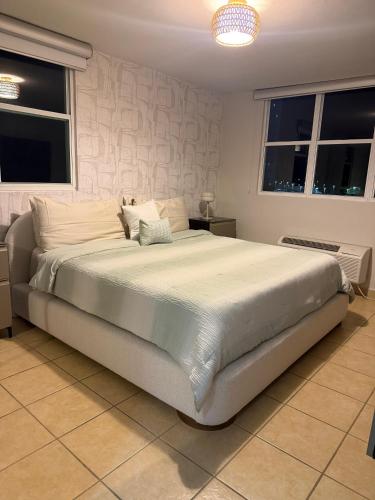 a large bed in a bedroom with two windows at Luxury Apartment with Ocean Views in Fajardo