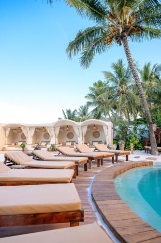 a resort with a pool and palm trees at Mala Boutique Hotel in Bwejuu