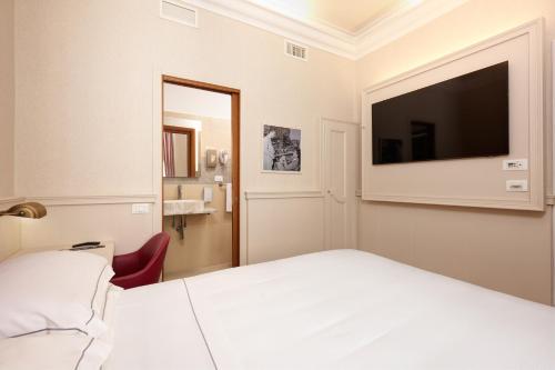 a bedroom with a white bed and a flat screen tv at Golden Tulip Rome Piram in Rome