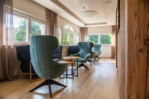 a waiting room with chairs and tables and windows at Hotel Continental in Andalo