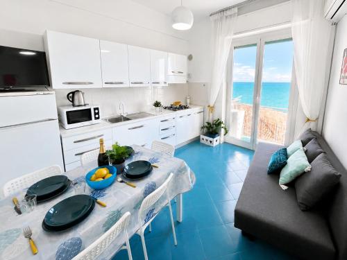 a kitchen and living room with a table and a couch at Vista Mare, Netflix & AC - Smeraldo Apartment in Laigueglia