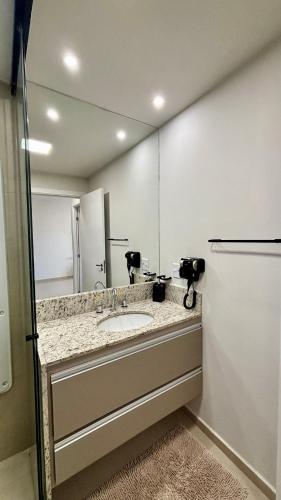 a bathroom with a sink and a mirror at Apartamento completo Studio 9 centro Pouso Alegre in Pouso Alegre