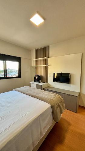 a bedroom with a large bed and a flat screen tv at Apartamento completo Studio 9 centro Pouso Alegre in Pouso Alegre