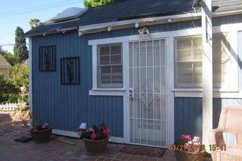 a blue shed with a white door and some flowers at Backyard Bungalow private guest house in Riverside