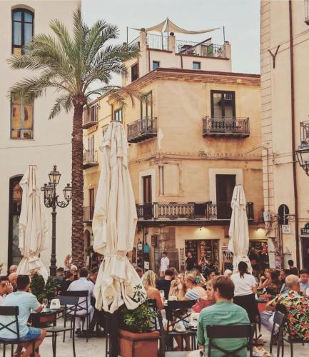 a group of people sitting at tables with umbrellas at Palazzo Villelmi in Cefalù