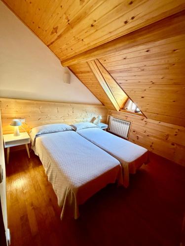 a bedroom with two beds in a wooden ceiling at Cal Quimet in Rialp