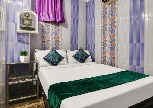 a bedroom with a white bed with a green blanket at Hotel Amaravathi Residency in Guntūr
