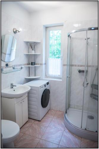 a bathroom with a shower sink and a washing machine at Mazury- dom wakacyjny in Pisz