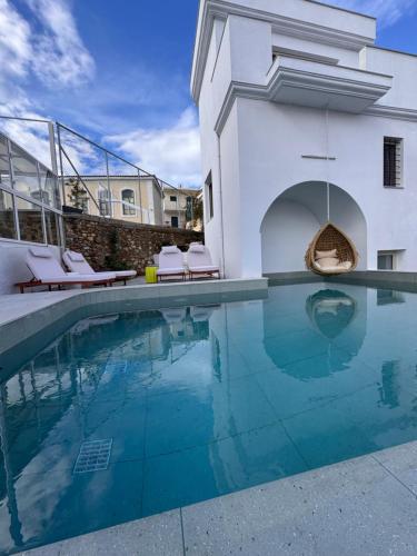 a swimming pool with chairs and a building at Rozmari Suites in Agia Galini