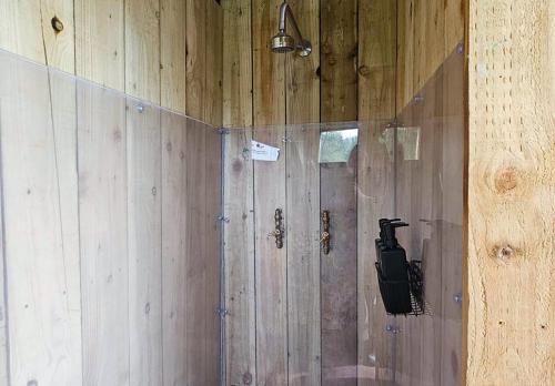 a shower in a wooden wall with a mirror at Roden Retreat in Aston