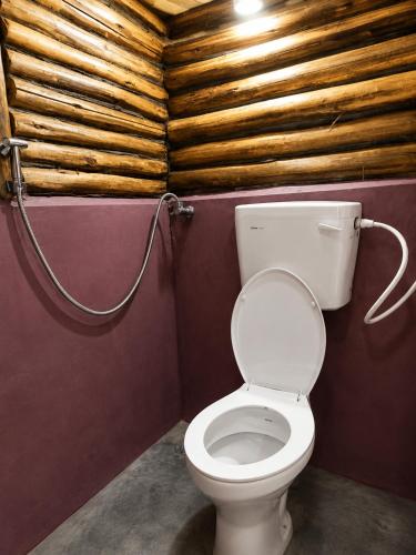 a bathroom with a toilet and a wooden wall at Sholanest Mud House and Farm Stay in Vattavada Near Munnar in Vattavada