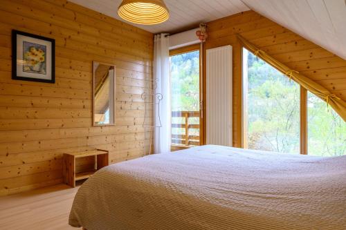a bedroom with a bed and a large window at Chalet Les Genêts 2 - Spa et Sauna in Saint-Amarin