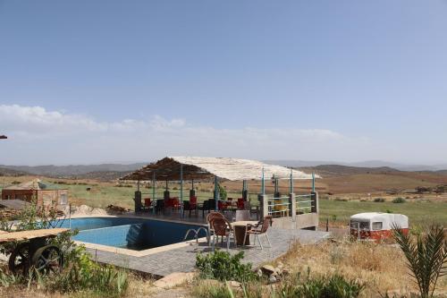 a pool with a gazebo and a table and chairs at Gîte Touften in Aït Aïouz