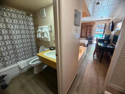 a bathroom with a sink and a toilet and a living room at Sunset Inn in Niagara Falls