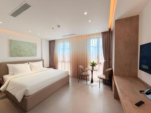 a bedroom with a white bed and a table and chairs at Sunday Boutique Hotel in Phú Quốc