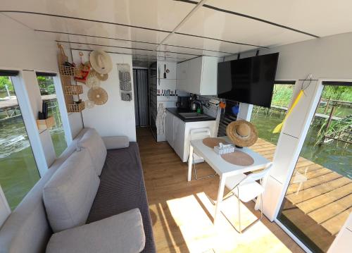 a living room with a couch and a table and a tv at Houseboat Bella in Tereszewo