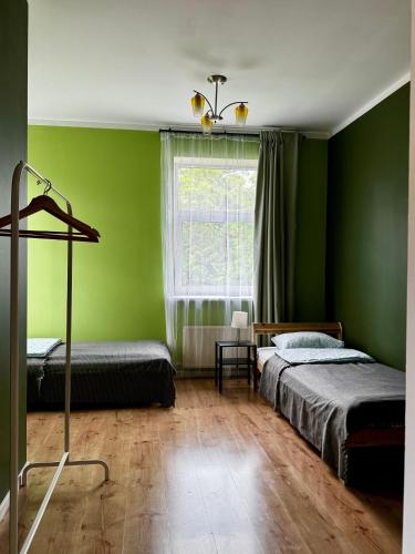 a green room with two beds and a window at Bauska Old Town Apartments in Bauska