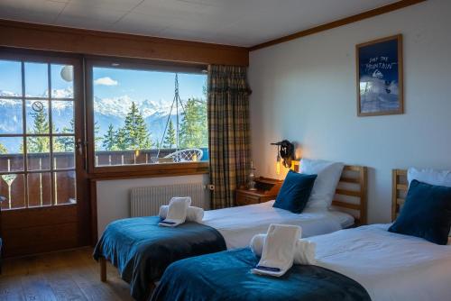 two beds in a room with a view of the mountains at Colorado Riders Chalet in Crans-Montana