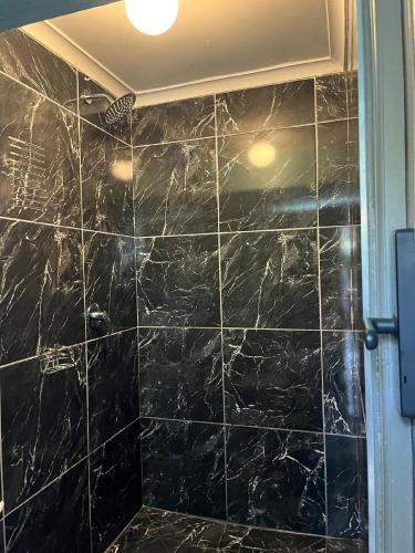 a bathroom with a black marble shower stall at Ojong's Self Catering Accommodation Bellville in Cape Town
