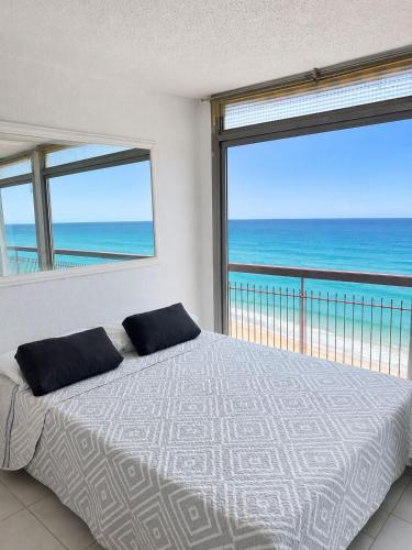 a bedroom with a bed with a view of the ocean at Apartamento Benidorm primera linea in Benidorm