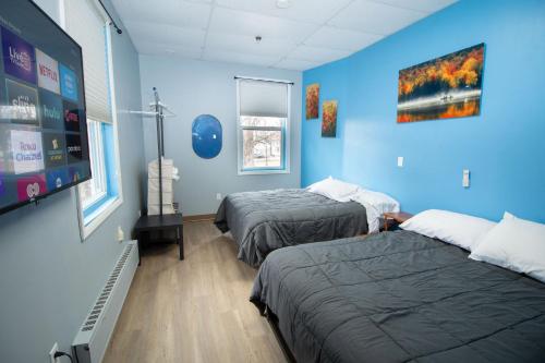 a room with two beds and a blue wall at Foothills Lodge & Cafe in Malone