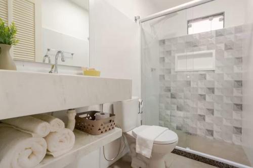 a white bathroom with a toilet and a sink at Villa Bela - Lofts - cama queen e ar-condicionado in Iguaba Grande