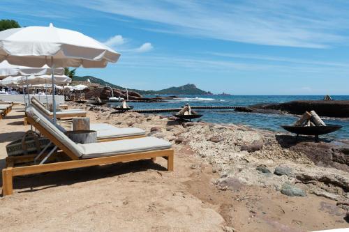 a group of lounge chairs and umbrellas on a beach at La Réserve Esterel in Saint-Raphaël