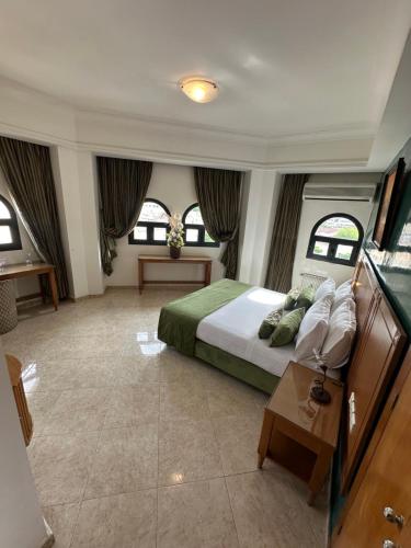 a bedroom with a bed and a table and windows at Hotel Mounia in Fez