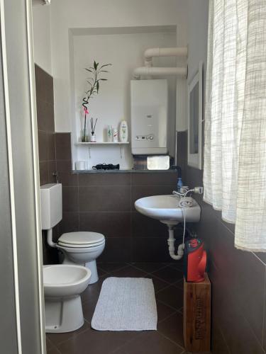 a bathroom with a white toilet and a sink at Pasa da sí in Alba