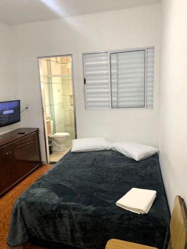 a bedroom with a bed and a bathroom with a television at kitnet 101 mob in Tatuí
