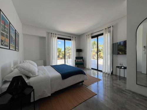 a white bedroom with a large bed and large windows at Dar El Musc Chambres d'hôtes in Sukrah