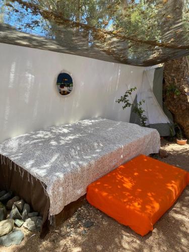 a bed with an orange pillow sitting in a room at Bedro Private Garden Studio & Outdoor Lounge 1 Min to Sea in Dahab
