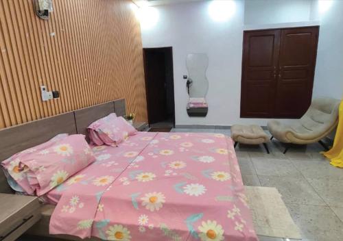a bedroom with a pink bed with flowers on it at SKYFORCE Bénin - Agatha in Porto-Novo