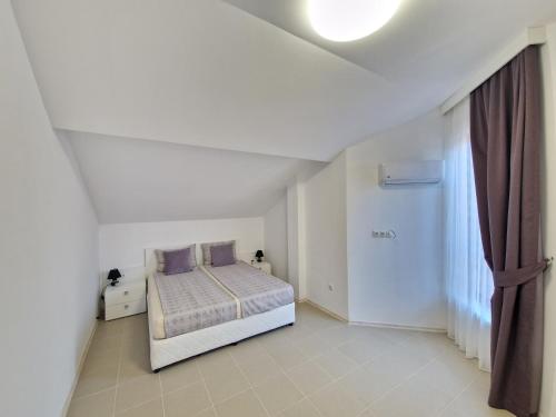 a white bedroom with a bed with purple pillows at INFINITY VIEW 8 Lozenets in Lozenets