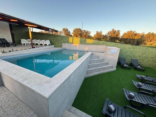 a swimming pool with chairs and a lawn at Casa dos Neto Santiago in Anadia
