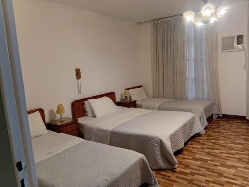 a hotel room with two beds and a chandelier at Hotel guido palace in Buenos Aires