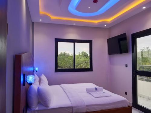 a bedroom with a white bed with a purple ceiling at Logements Majeo in Bikondo