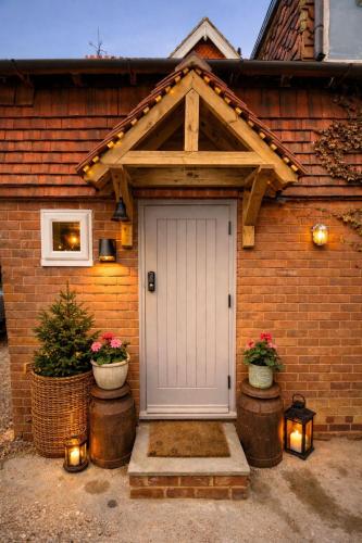 a house with a white door and two potted plants at 1 Bridge Rd in Cranleigh
