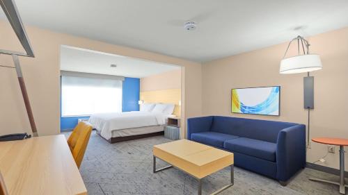 a hotel room with a bed and a blue couch at Holiday Inn Express Hotel & Suites Milwaukee Airport by IHG in Greendale