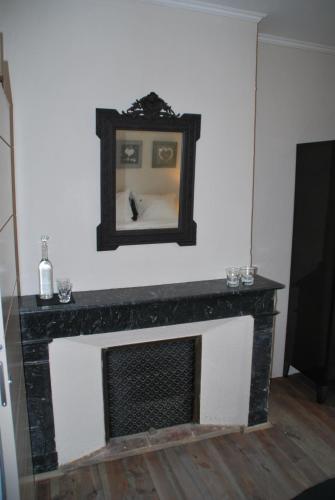 a fireplace with a mirror above it in a living room at La Maison au Puits in Cordes-sur-Ciel