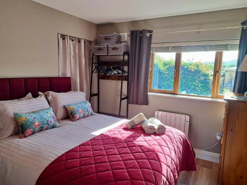 a bedroom with a bed with a red blanket and two stuffed animals on it at 9 Suíomh Alainn in Kilgarvan