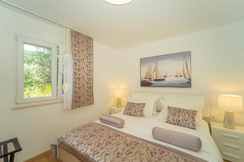 a white bedroom with a large bed and a window at Villa Green Bay in Vela Luka